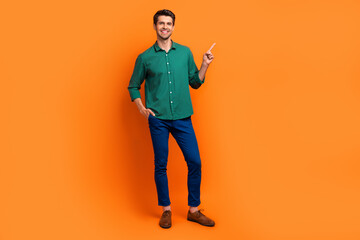 Full body photo of young man wear green shirt pants classics shoes direct finger brand store clothes isolated on orange color background