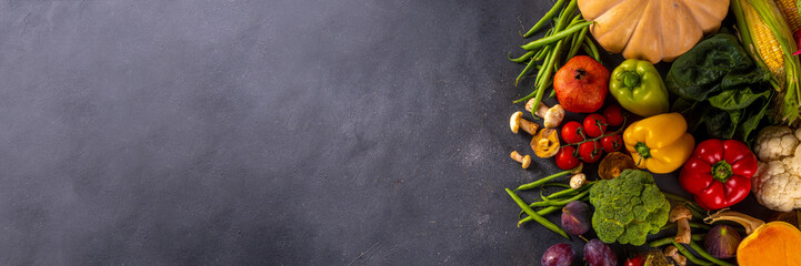 Autumn vegetable preparation dinner background. Food background with organic fresh farm raw veggies, pumpkin, corn, fruits, mushrooms, salad leaves, greenery, Ingredients for cooking with copy space.