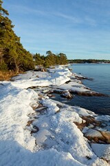Winter seashore with water, ice, trees and rocks, Kopparnäs, Finland.