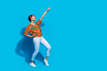 Full body portrait of overjoyed pretty lady dance look direct finger empty space ad proposition isolated on blue colors background