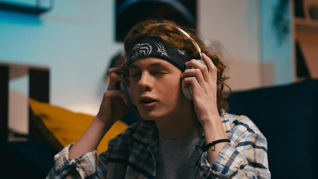 Teen boy putting headphones on and playing imaginary drums, enjoying music