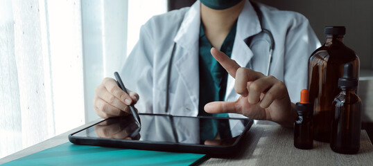 Fototapeta premium Research and experiments in the pharmaceutical or chemical industry. Female scientist in lab or chemist making notes on laptop by studying liquid in test tube. Scientists working on the background.