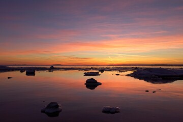 Fototapeta na wymiar Sunset in winter on sea coast on the island of Lauttasaari with unfrozen water, Helsinki, Finland.