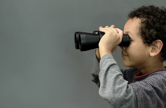 boy looking  through binoculars on grey background with people stock image stock photo