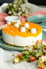 Mango Yogurt Cake topping with pistachio fork and flowers served in plate isolated on napkin side view cafe bake food