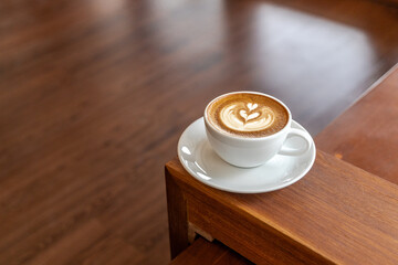 Hot latte coffee in a cup placed on a wooden table in the morning