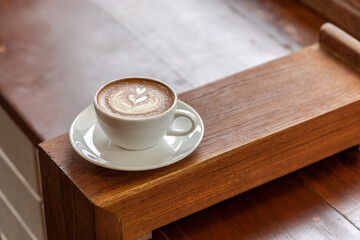 Hot latte coffee in a cup placed on a wooden table in the morning