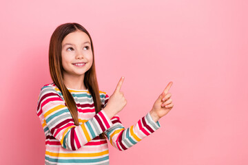 Photo of funny little cute daughter pointing finger novelty empty space advertisement interesting news isolated on pink color background