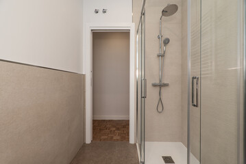 Small bathroom in an apartment with shower cabin with glass partitions and walls of marble tiles...