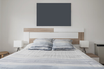 A double bedroom with white wooden headboard, fabric bedspread with matching cushions and twin lamps