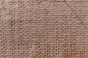 A wall of exposed clay bricks with light brown paint