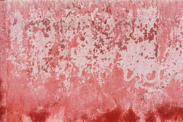 A cement wall painted red with the paint completely peeling off