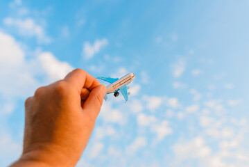 Hands of man holding a toy plane and have dreams wants to be a pilot.On a background blurred clouds sun blue sky.