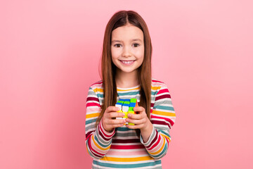 Photo of optimistic small little funky kid girl playing rubik cube toy logic puzzle solving strategy isolated on pink color background