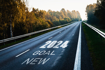 New year,new goal 2024 or start straight concept.Inscription New goal 2024 on the road of asphalt.Road at sunset.Concept of planning,challenge,career path,business strategy,opportunity and change.