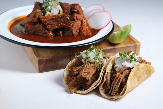 Birria tacos with traditional birria stew plate in background, authentic Mexican food