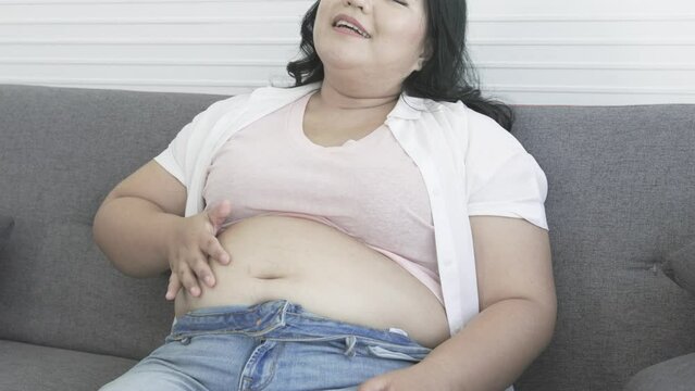 chubby asian woman smacks her belly happily after eating food the pleasure of eating fat woman