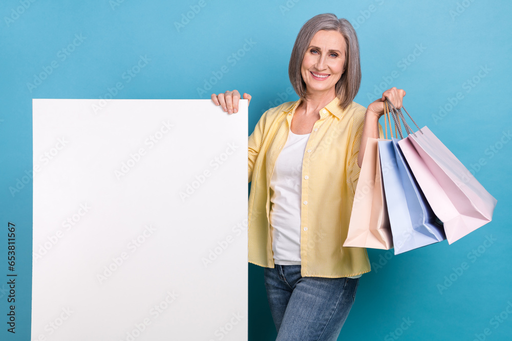 Sticker Photo of nice aged person hold store mall bags demonstrate empty space placard isolated on blue color background