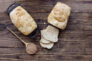 Above table top view of freshly baked whole wheat bread loaves with wooden spoon filled with grain. Overhead.