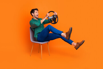 Full body cadre of young man sitting chair steering wheel driver excited drunk alcoholic accident crash isolated on orange color background