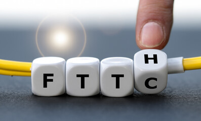 Hand turns dice and changes the expression Fiber to the curb (FTTC) to Fiber to the home (FTTH). Symbol for connecting residences directly with optical fibers. - obrazy, fototapety, plakaty