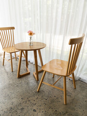 The wooden chair and table set in the minimal style with the blooming flower.