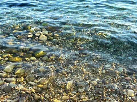 Sea shore clear water with smooth pebbles stones 