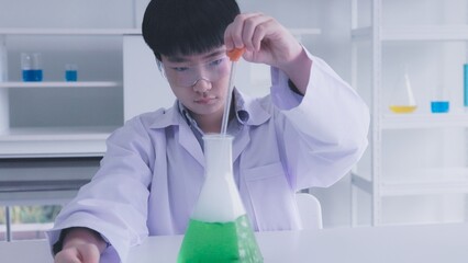 Asian schoolboy doing chemistry experiment in science lab