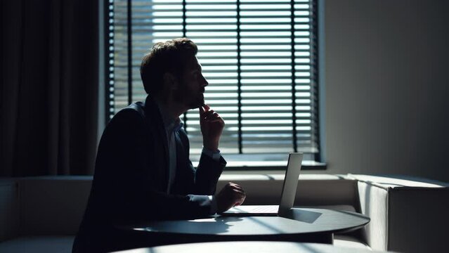 Creative manager being focused on developing detailed plan for implementation of new business project. Formally dressed man thinking on ideas and typing on keyboard of personal remote computer.