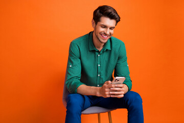 Photo of young successful businessman brunet hair chat with colleagues corporate dialogue hold phone isolated on orange color background