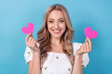 Photo of cheerful sweet girl dressed white top rising two pink heart isolated blue color background