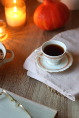 Vintage books, reading glasses, cup of tea or coffee, bowl of cookies, pumpkin and lit candles on the table. Hygge at home, fall atmosphere. Selective focus.