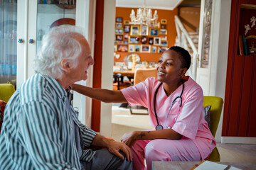 Young African American female caregiver consulting her senior patient at home