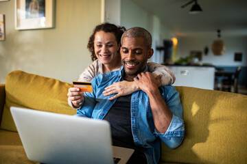 Mixed couple online shopping together on the laptop at home