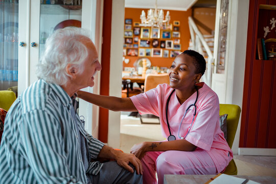 Young African American female caregiver consulting her senior patient at home