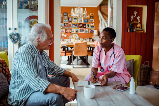 Young African American female caregiver consulting her senior patient at home