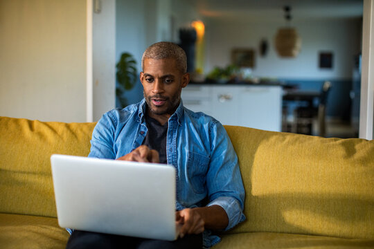 Middle aged man using the laptop on the couch at home