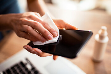 Young woman disinfecting her smartphone at home