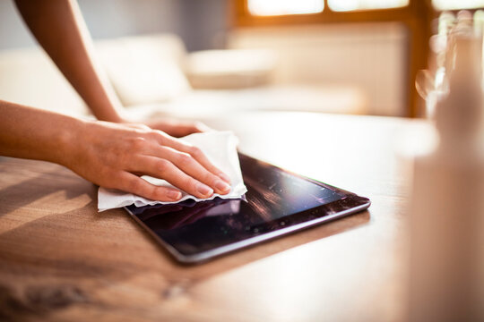Young woman disinfecting her tablet at home