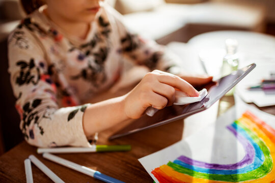 Young girl disinfecting his tablet in the living room at home