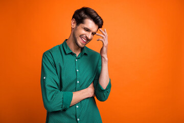 Photo of good mood positive guy wear green shirt smiling empty space isolated orange color background