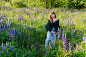 A woman in a green blouse in a field with lupines