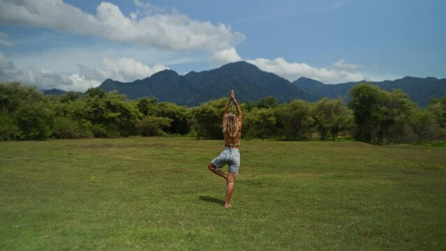 Tourist Woman at the mountains, freedom. Happy girl relaxing and doing yoga on the field with mountain view. 