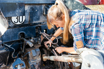Focused farmer connecting machinery on a tractor in countryside during daytime