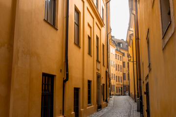 Medieval yellow stone houses in urban historic narrow alley in Stockholm Old Town Gamla Stan by Bollhusgränd street in bright summer day
