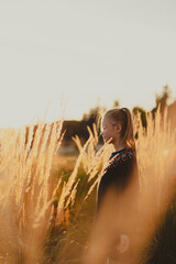 girl standing in a dry field during the golden hour in the autumn evening
