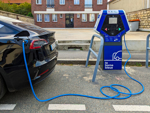 Arcueil, France - 28 septembre 2023: Station de recharge de v&eacute;hicules &eacute;lectriques appartenant au r&eacute;seau fran&ccedil;ais "La borne bleue" en cours de charge d'une voiture &eacute;lectrique dans la rue