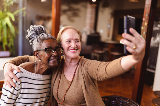 Amigas idosas se divertindo, tirando fotos com o smatphone.