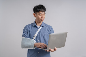 Businessman wears cast on his broken arm after an accident and and holding computer laptop.