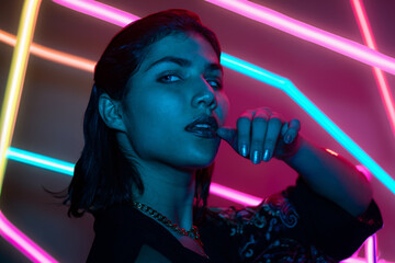Portrait of young woman in neon on dark studio background; cyber monday concept